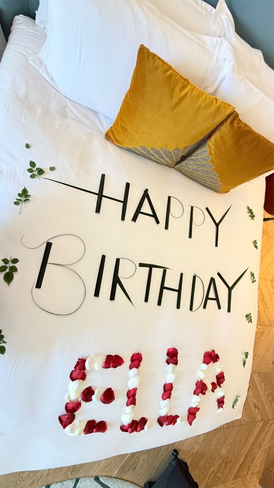 A Happy Birthday message spelt in petals on the bed